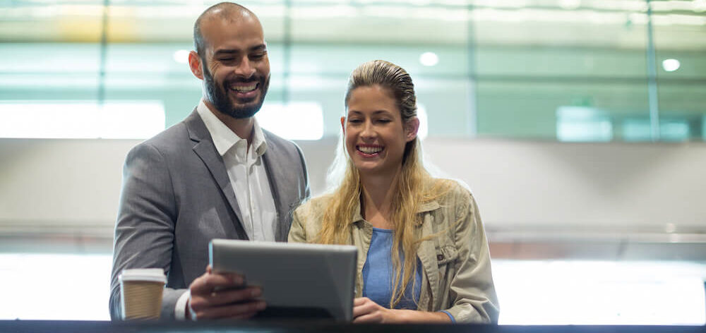 smiling-couple-using-digital-tablet-waiting-area